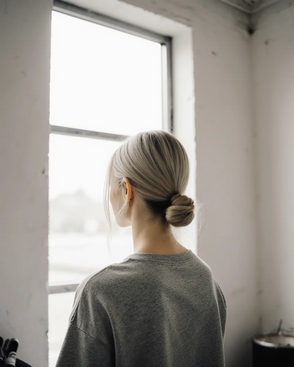 Chignon bas travaillé, vu de dos, dans la lumière de la verrière